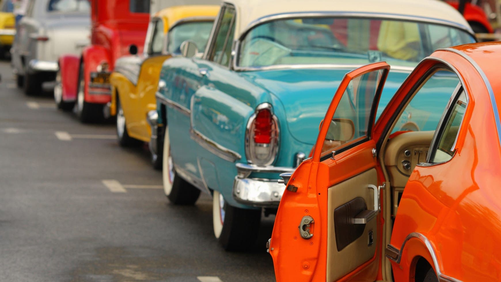 Several Antique Cars Lined Up on the Road