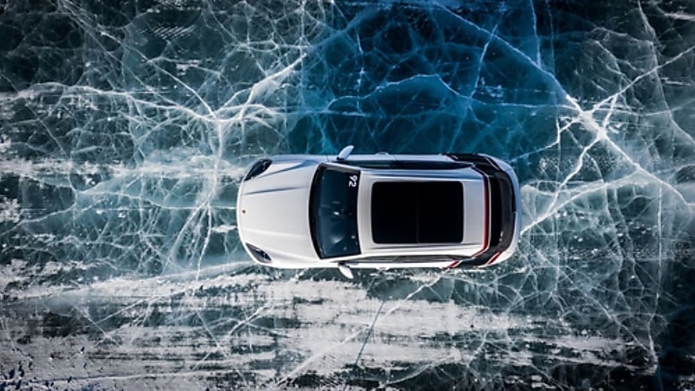 White Porsche 911 driving on an iced over lake.